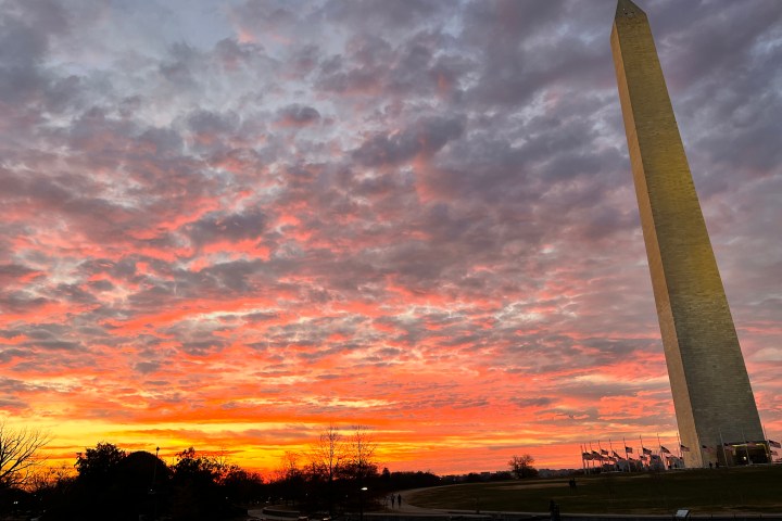 Washington Monument at sunset with vibrant orange and purple clouds.