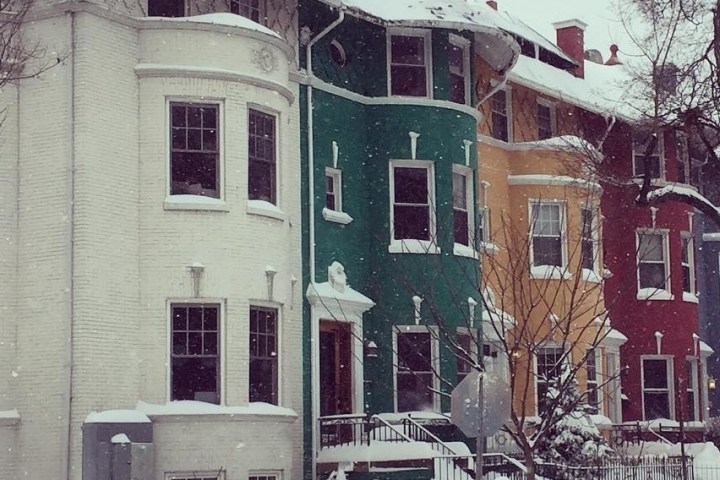 a house covered in snow in front of a brick building