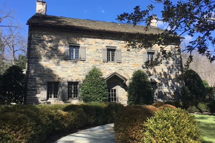 a house with bushes in front of a brick building